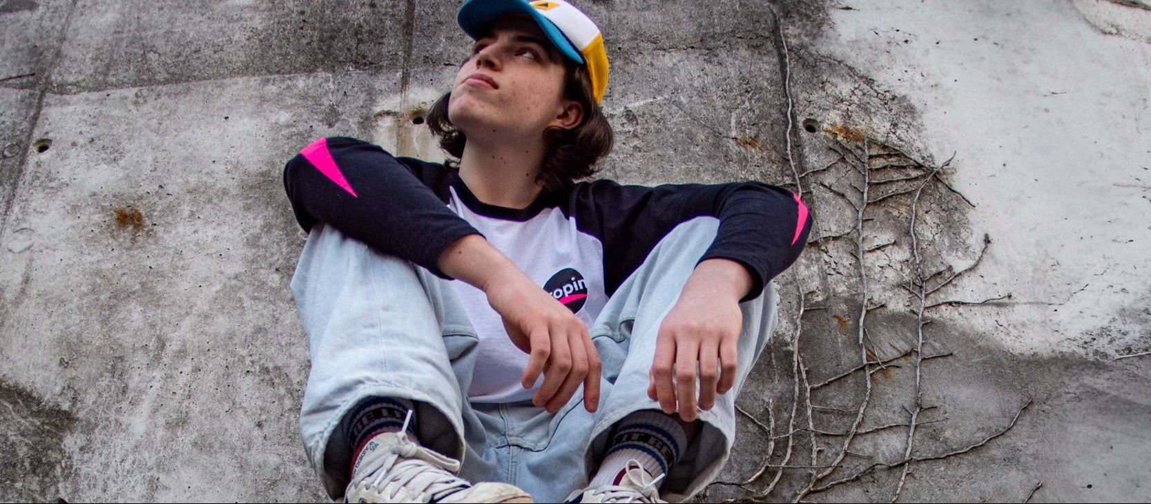 Person sitting on a concrete pipe against a textured wall.